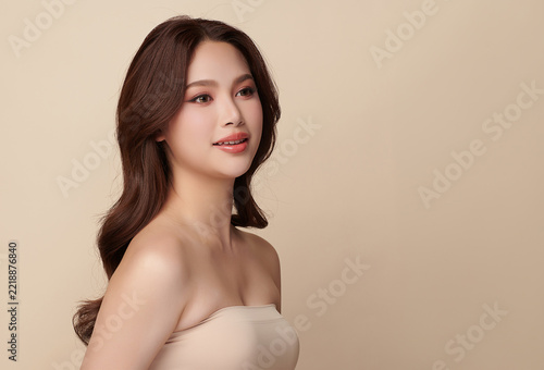 A beautiful young Asian woman with clean, fresh skin against a beige background. Skincare, facial treatment, cosmetology, beauty, and spa. An elegant portrait of an Asian woman.