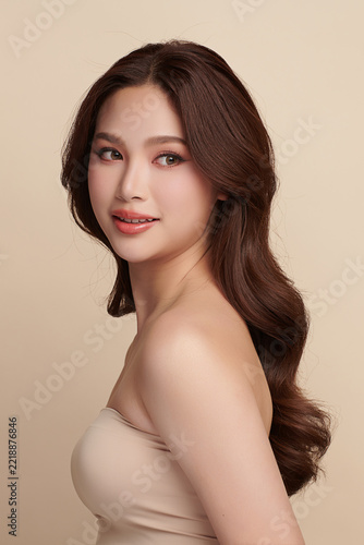 A beautiful young Asian woman with clean, fresh skin against a beige background. Skincare, facial treatment, cosmetology, beauty, and spa. An elegant portrait of an Asian woman.
