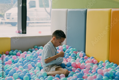 An Asian little boy is playing in an indoor ball pool; an Asian family is traveling and relaxing