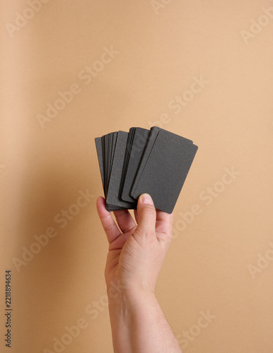 A woman's hand holds a stack of blank black paper business cards