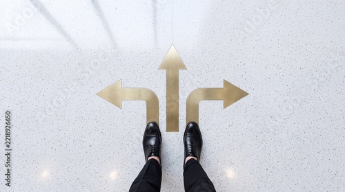 Businessman standing before three golden directional arrows on a white floor, facing a crossroad and making a strategic choice for career growth, business path, and future success.