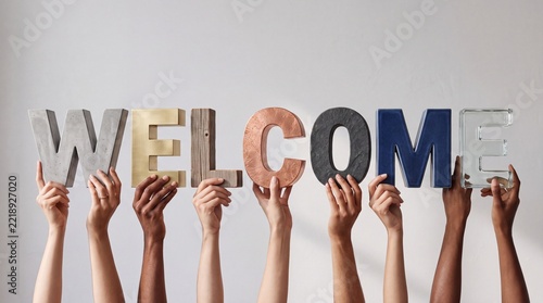 Group of Diverse Hands Holding Textured 3D Letters Spelling Welcome in Various Materials including Wood Metal and Concrete for Premium Business Hospitality and Inclusion Concept