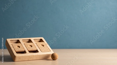 Minimalist studio product shot of a wooden Montessori object permanence box and cork ball on a table, symbolizing a quiet moment of learning and discovery in early childhood education.