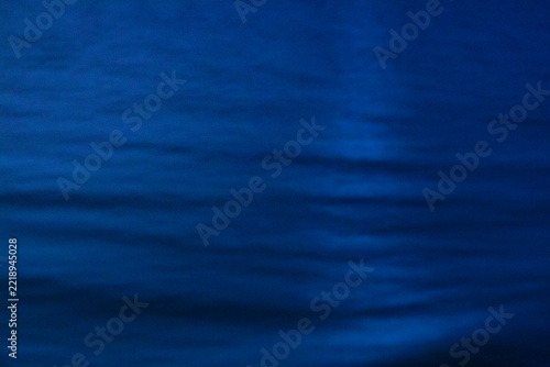 The ocean surface, midnight blue colours in the darkness, reflections and ripples on the water.