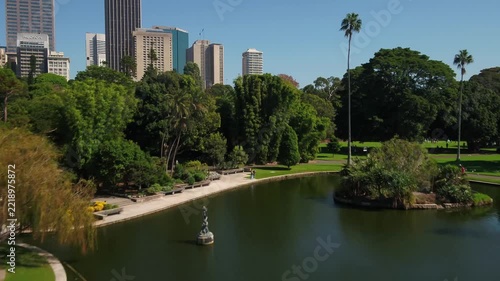 Drone Flying Over Public Park Pond with City Skyline in Background