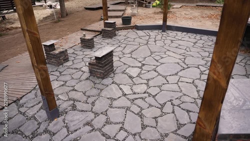 Newly installed crazy paving flagstone patio in a backyard landscaping project with wooden posts