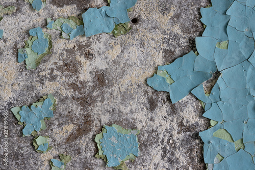 Blue peeling paint on the wall. Old concrete wall with cracked flaking paint. Weathered rough painted surface with patterns of cracks and peeling. High resolution texture for background and design.
