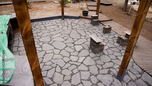 Newly installed crazy paving flagstone patio in a backyard landscaping project with wooden posts