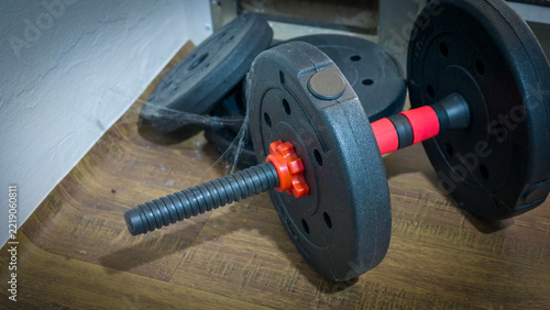 Adjustable dumbbell handle with weight plates: A close-up shot of an adjustable dumbbell handle with a spiderweb clinging to it.
