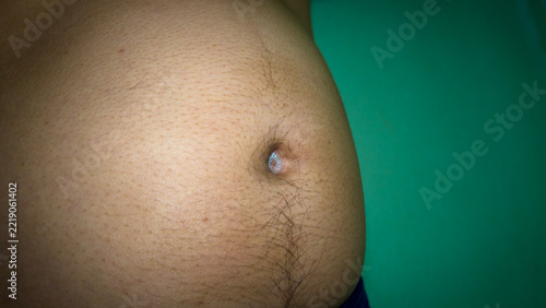 Navel Close-up: A detailed close-up shot focuses on a human navel, revealing its texture and surrounding skin, set against a teal background.
