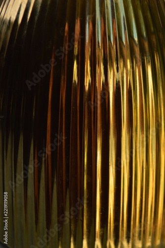 Abstract golden background with vertical ribbed texture and warm metallic light reflections