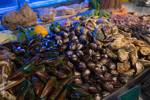 A colorful selection of fresh mussels, clams, oysters, squid, and other shellfish arranged on ice for seafood dining.