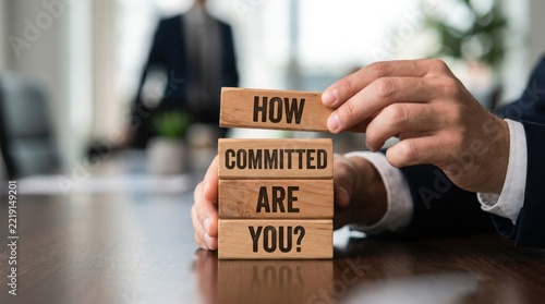 Hands arranging wooden blocks with the question how committed are you