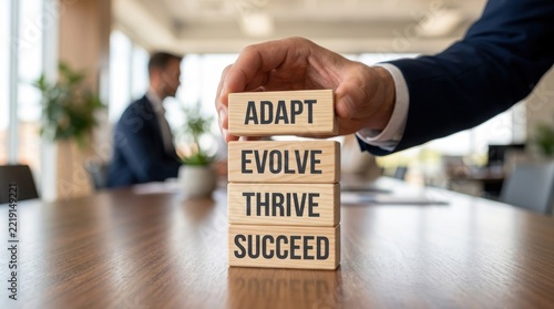Hand building a tower of blocks with words adapt evolve thrive succeed