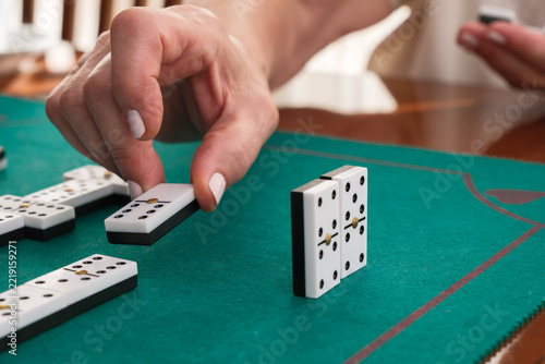 Hand placing domino on green felt table
