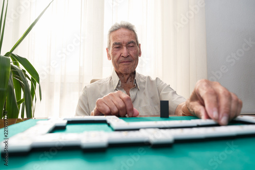 Senior man playing dominoes, enjoying leisure time at home