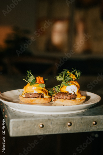 Obraz na plátně Two eggs benedict with hollandaise sauce on a rustic metal plate
