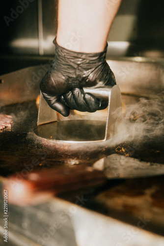 Chef uses metal tool to baste meat in a hot pan during cooking