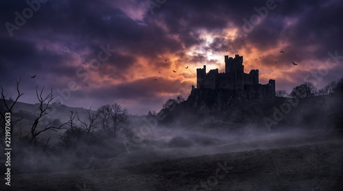 Medieval castle silhouette standing proudly under a dramatic dark purple stormy sky.