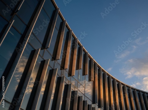Modern glass office facade with bronze fins at sunset