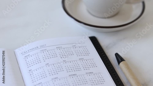Calendar 2027 in notebook with coffee cup.