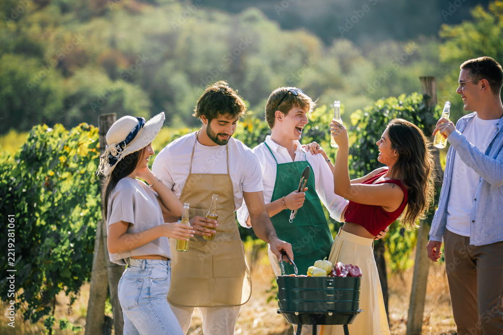 Naklejka premium Friends enjoying drinks and preparing food together among grapevines