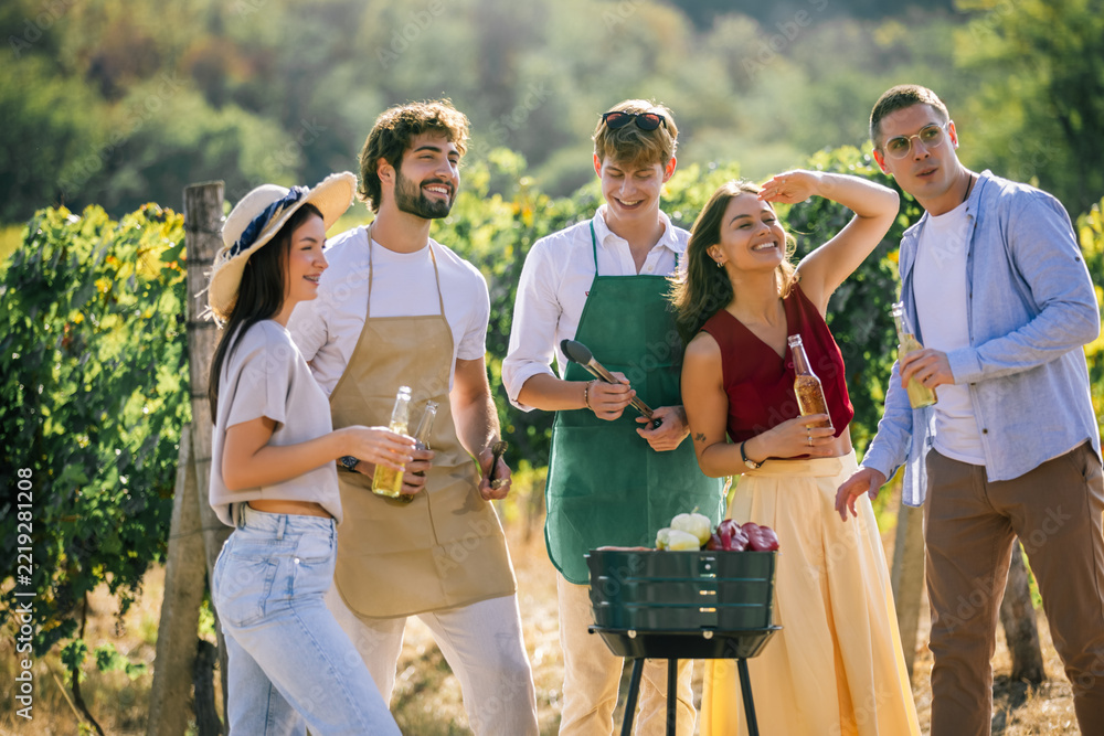 Fototapeta premium Group of friends enjoying an outdoor meal preparation in a vineyard