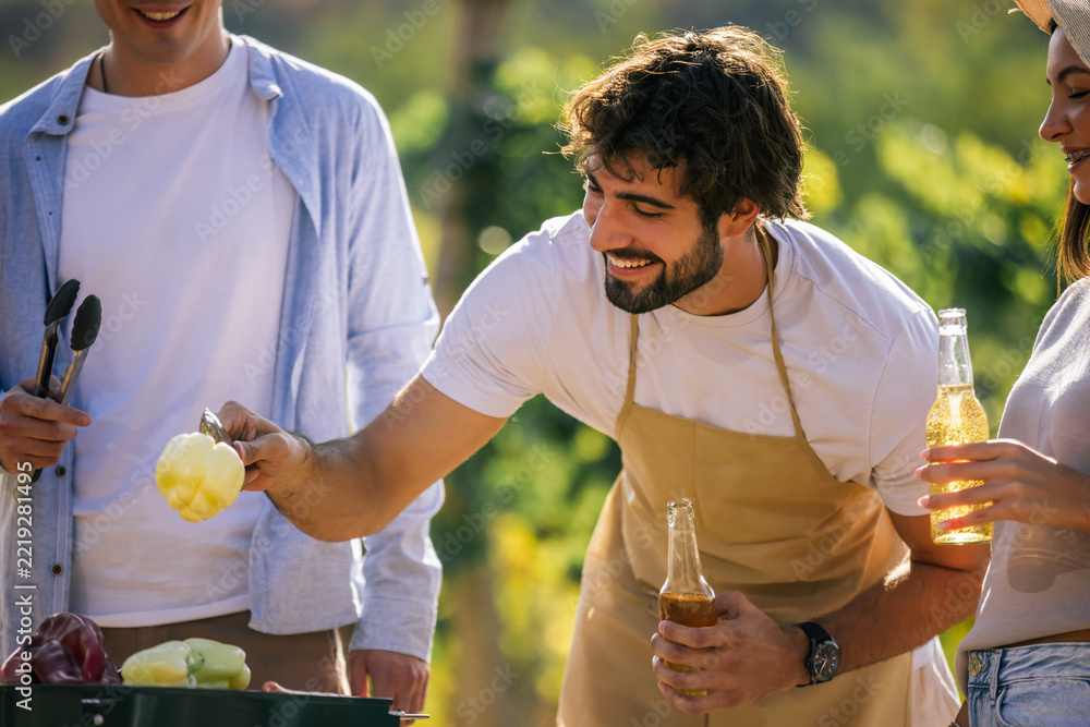 Fototapeta premium Man holding fresh ingredients while friends prepare food outdoors
