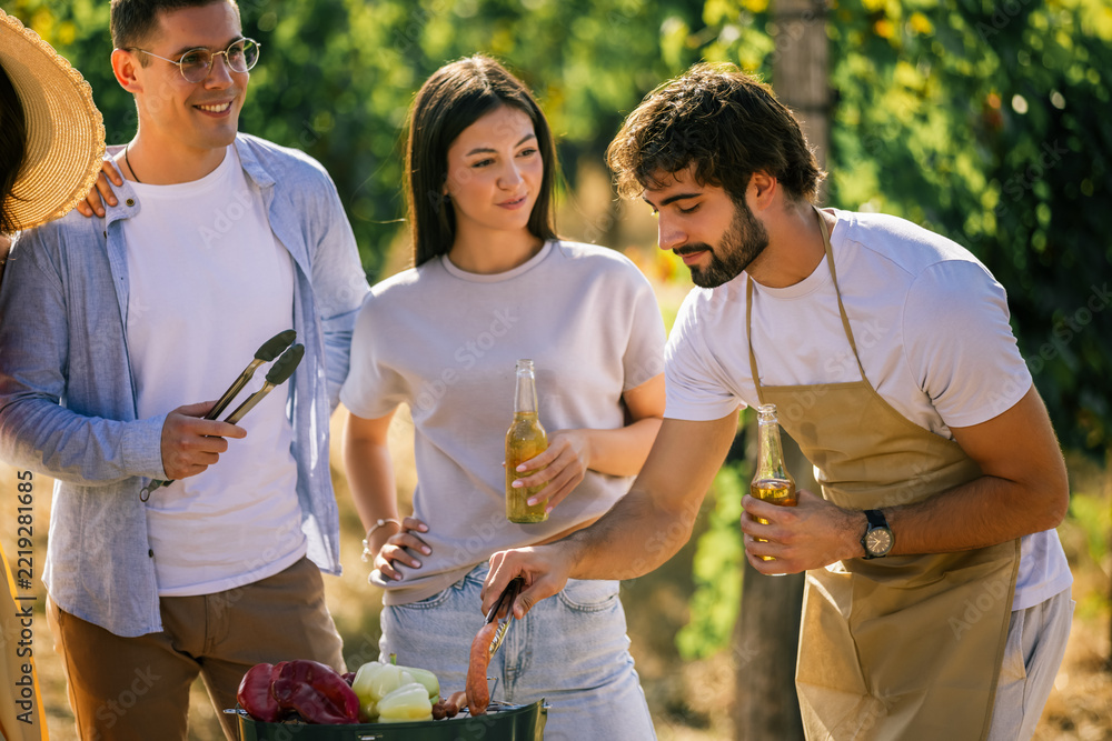 Fototapeta premium Friends preparing food together while enjoying a vineyard picnic