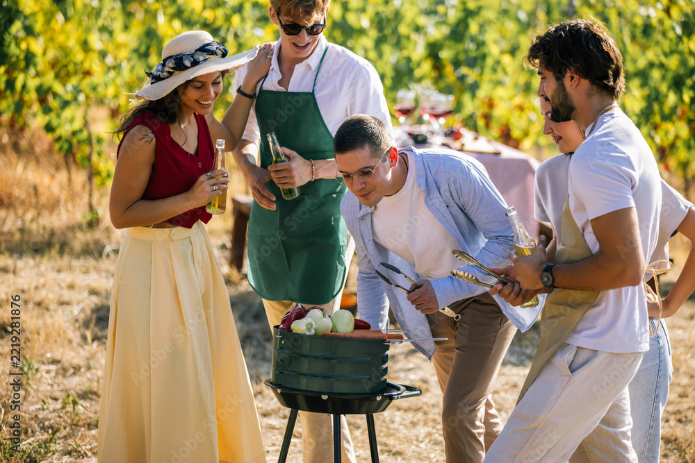 Fototapeta premium Friends cooking together around an outdoor grill in a vineyard