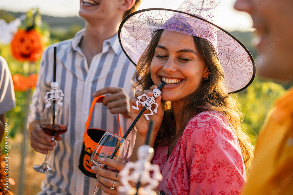 Fototapeta premium Woman in witch costume enjoying a Halloween vineyard celebration