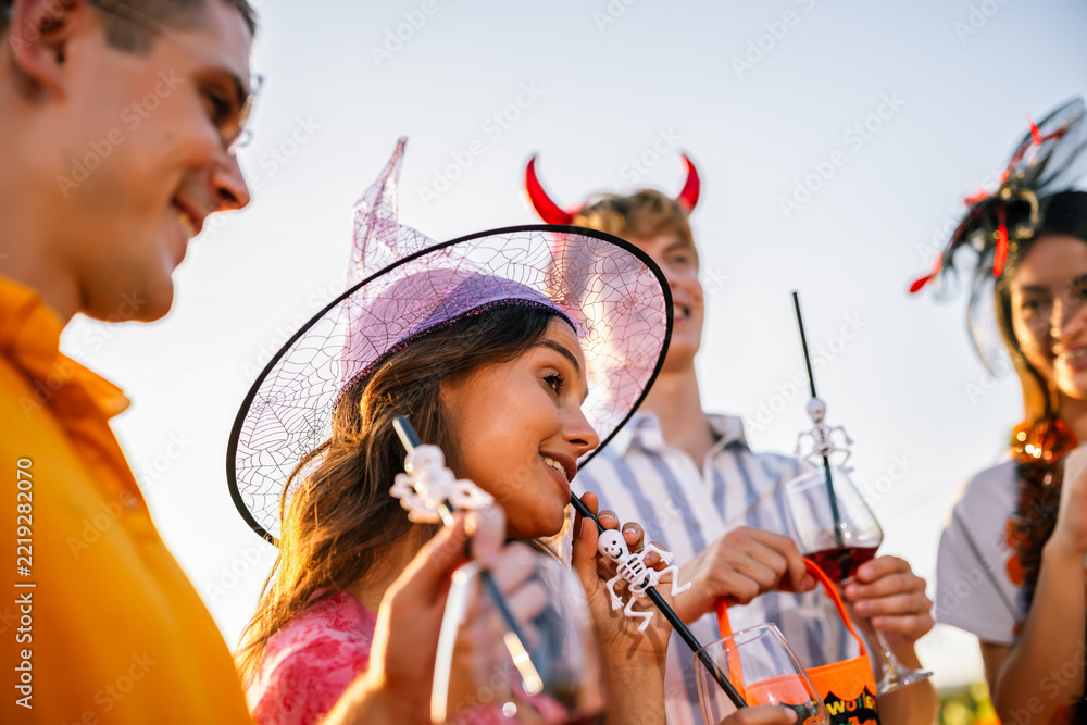 Naklejka premium Friends celebrating Halloween outdoors with a woman in a witch hat