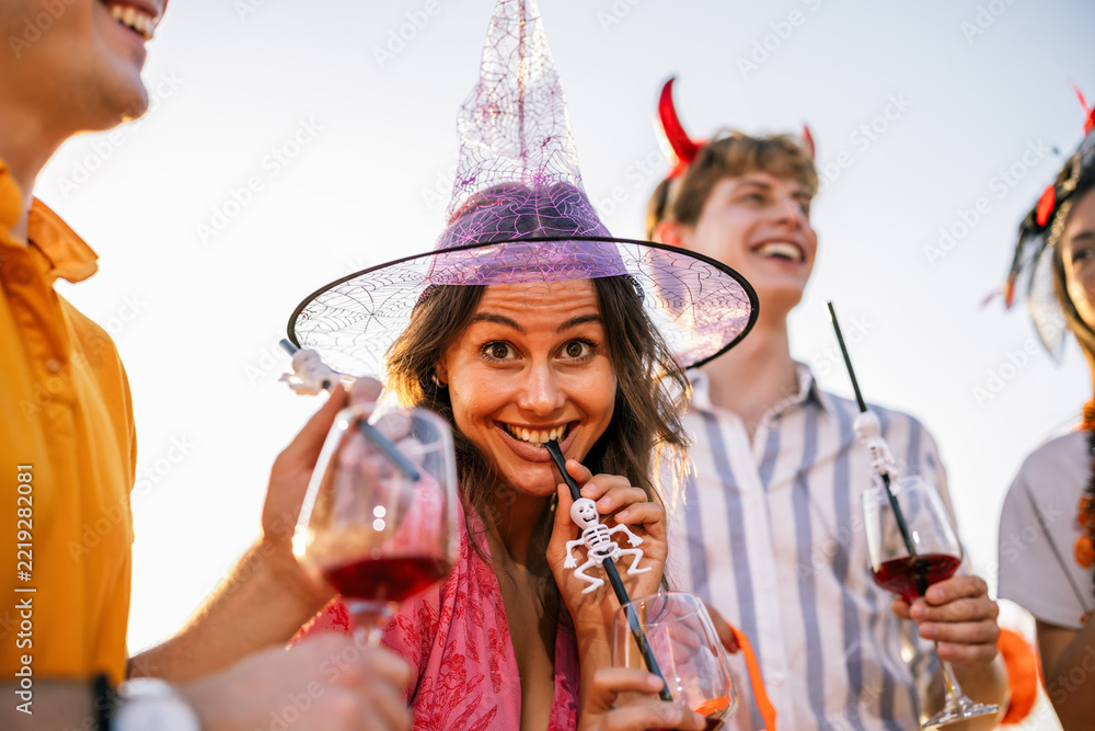 Fototapeta premium Smiling woman in a witch hat celebrating Halloween with friends