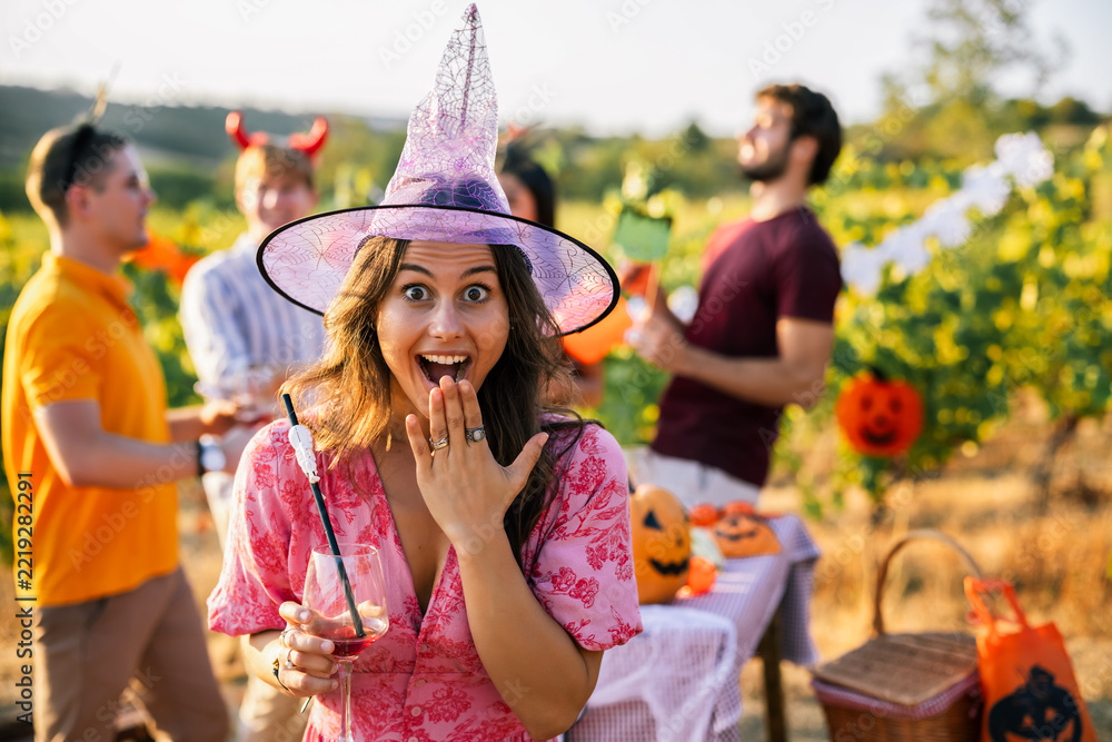 Fototapeta premium Surprised woman in witch costume enjoying a Halloween vineyard party