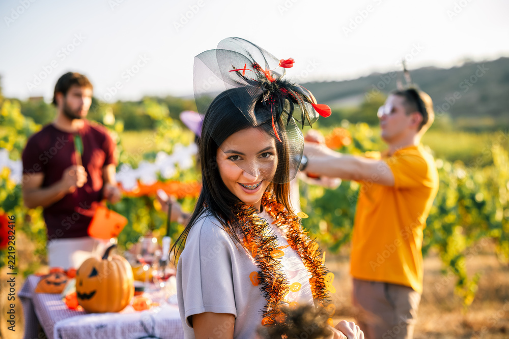 Fototapeta premium Smiling woman wearing a Halloween headpiece at an outdoor vineyard party