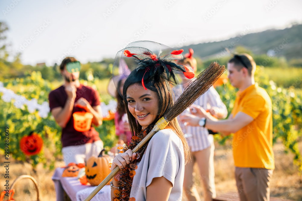 Fototapeta premium Woman carrying a decorated broom during a Halloween celebration in a vineyard
