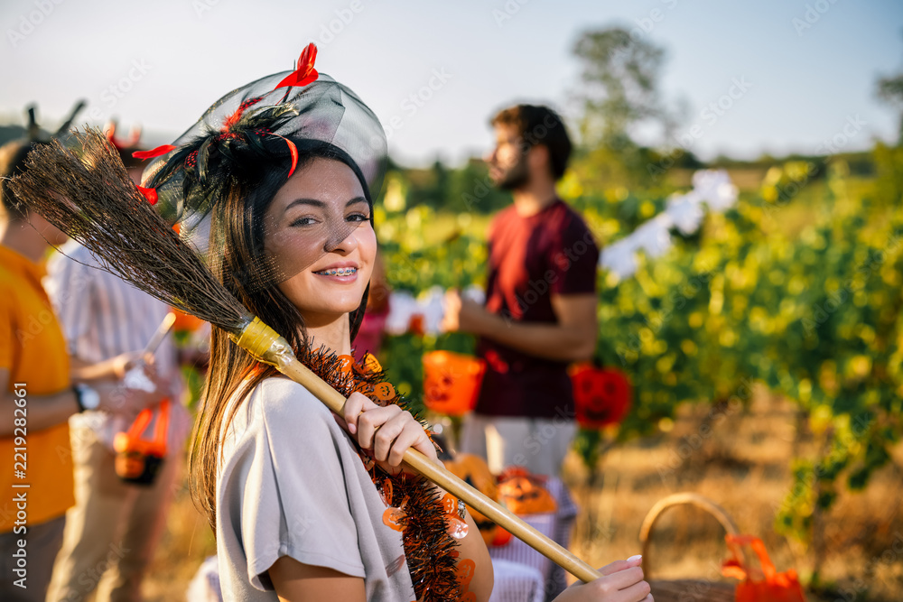 Naklejka premium Woman in Halloween costume posing with a decorated broom among grapevines