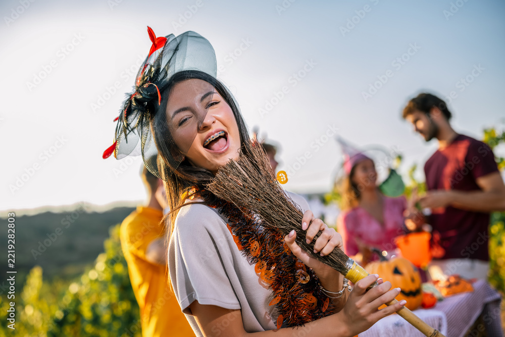 Fototapeta premium Woman in Halloween costume carrying a decorated broom during a vineyard party