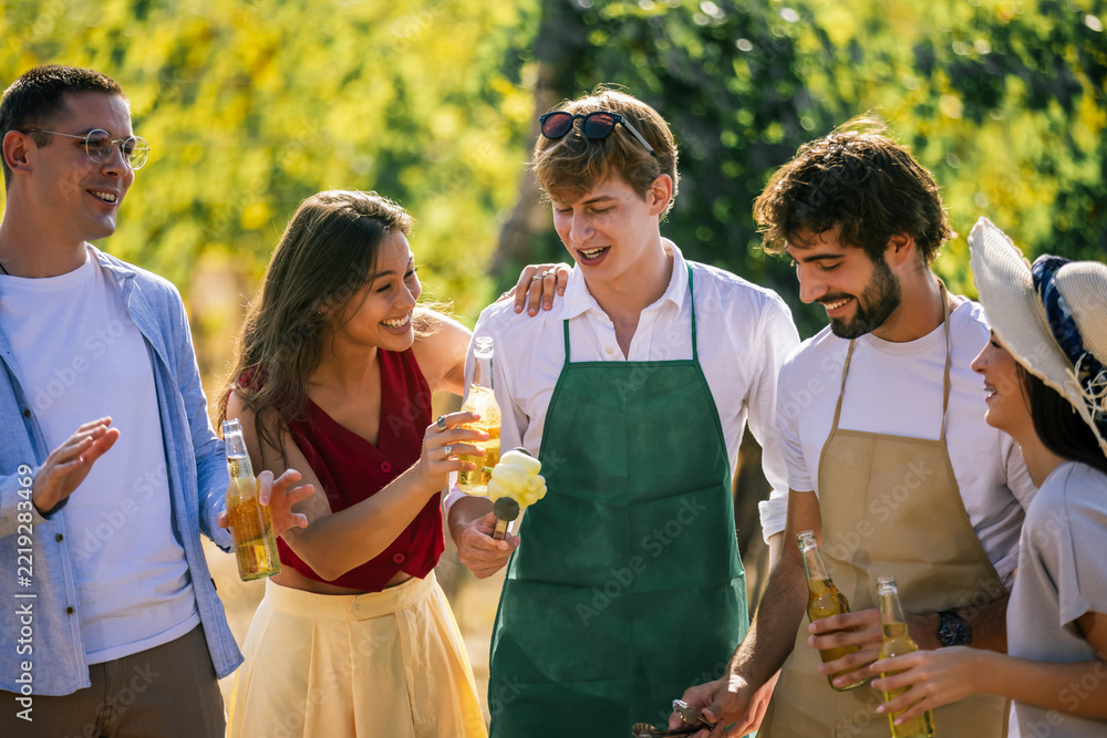 Fototapeta premium Friends talking and preparing food together at a vineyard gathering