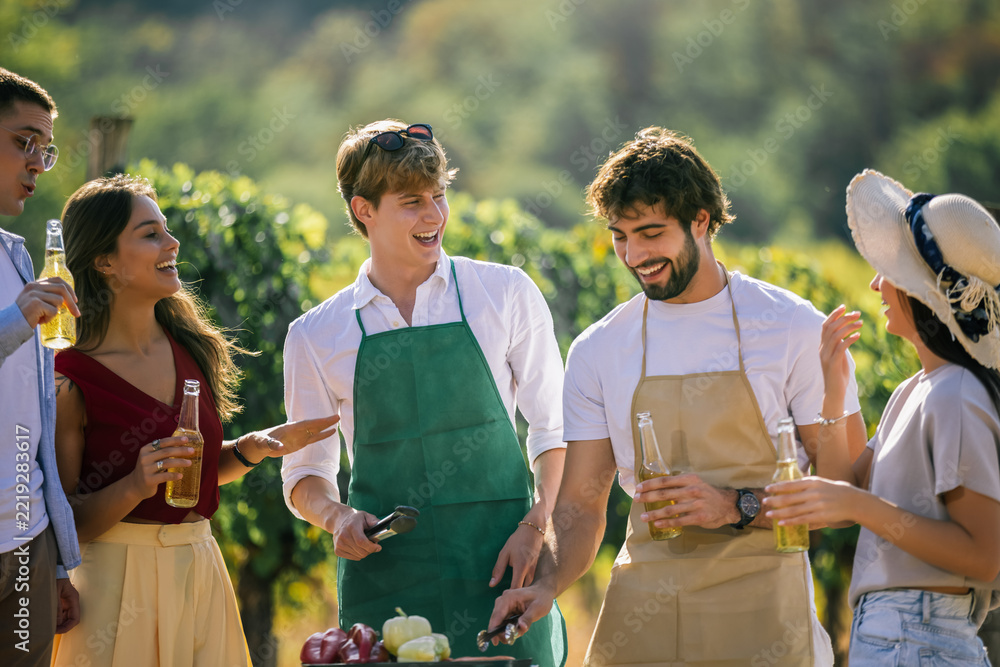 Fototapeta premium Group of friends chatting beside an outdoor food preparation station