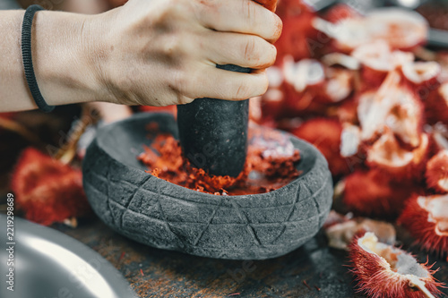 View of a person grinding red achiote seeds in a traditional stone mortar in Puerto Viejo de Talamanca, Limon Province, Costa Rica.