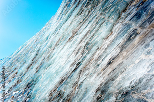 Close-up view of the textured ice surface, revealing intricate patterns, cracks and layers of glacial ice