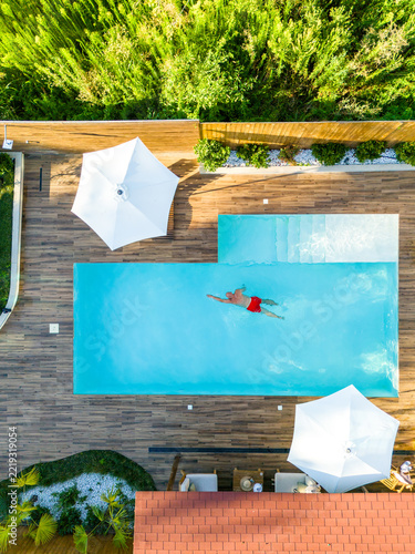 Top-Down Shot of Man Swimming in High-End Villa Pool. Concept of serene lifestyle and upscale comfort
