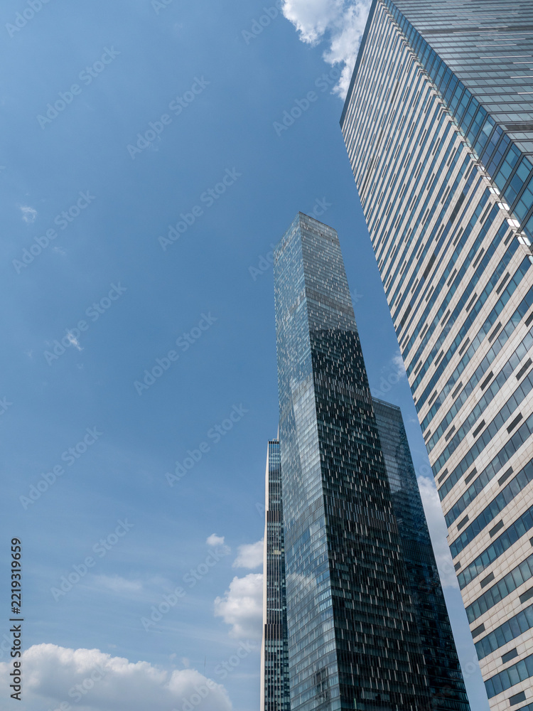Fototapeta premium Modern glass skyscrapers with reflective facades rising against a clear blue sky in an urban setting