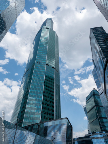 Modern glass skyscrapers with reflective facades rising against a clear blue sky in an urban setting