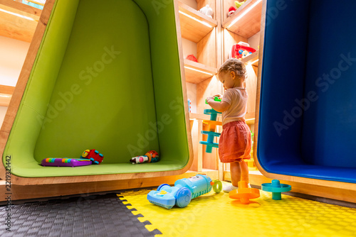 Child exploring a modern playroom with soft flooring, creative shelves, and fun activity toys