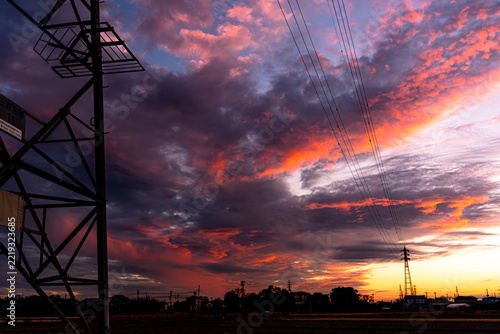 夕焼け空を背景にシルエットで浮かぶ送電鉄塔と電線