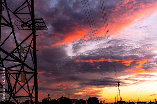 夕焼け空を背景にシルエットで浮かぶ送電鉄塔と電線