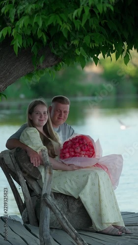 A smiling young couple sits by the river. Romantic date concept.