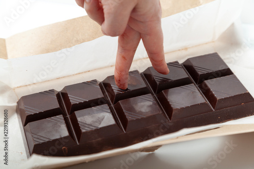 Fingers walking across a large chocolate bar